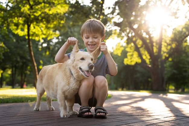 Niño sonriente de tiro completo y perro en el parque