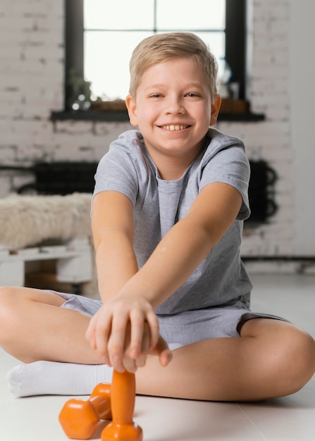 Foto gratuita niño sonriente de tiro completo con pesas