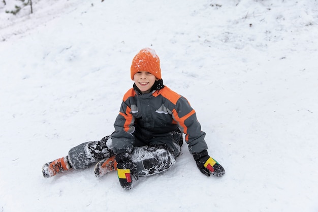 Niño sonriente de tiro completo sentado al aire libre