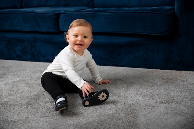 Niño sonriente de tiro completo sentado en la alfombra