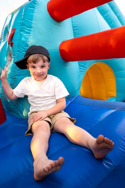 Foto gratuita niño sonriente de tiro completo sentado en la casa de rebote