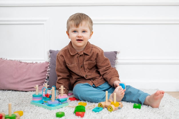 Niño sonriente de tiro completo sentado con juguetes