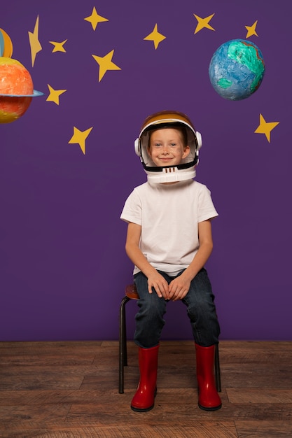 Foto gratuita niño sonriente de tiro completo sentado en una silla