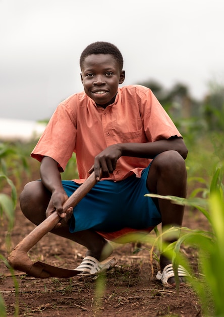 Foto gratuita niño sonriente de tiro completo trabajando al aire libre