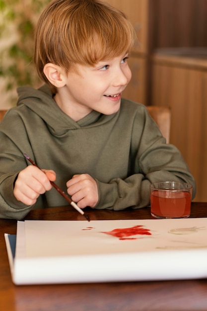 Niño sonriente de tiro medio con acuarelas