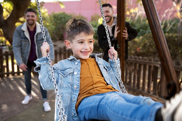 Niño sonriente de tiro medio en columpio