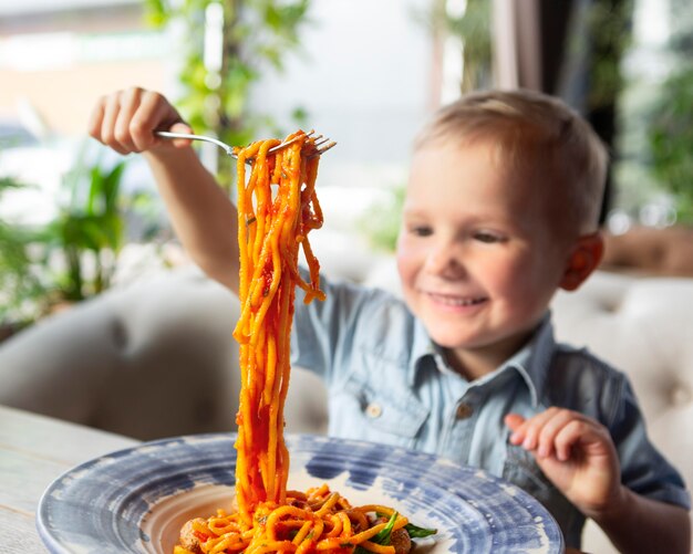 Niño sonriente de tiro medio con espaguetis