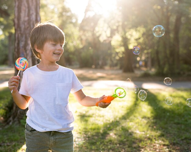 Niño sonriente de tiro medio con globos de jabón