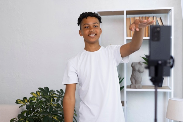 Foto gratuita niño sonriente de tiro medio grabando con teléfono