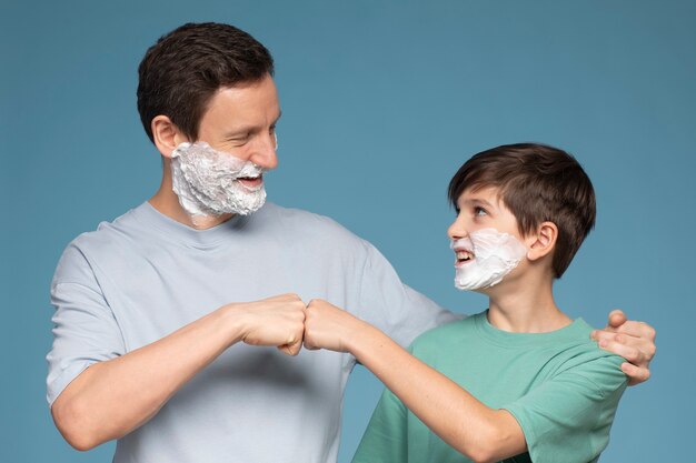 Niño sonriente de tiro medio y hombre con crema de afeitar