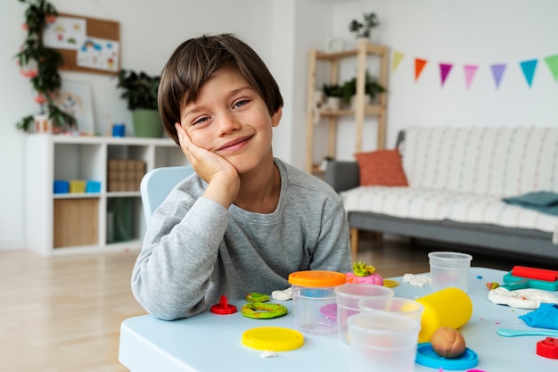 Niño sonriente de tiro medio con plastilina