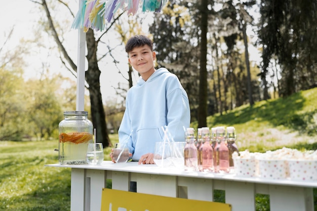 Niño sonriente de tiro medio con puesto de limonada