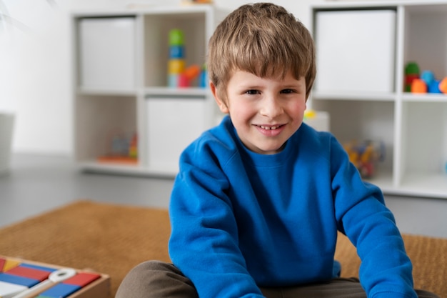 Niño sonriente de tiro medio sentado en el piso