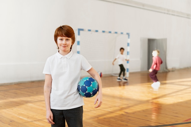 Niño sonriente de tiro medio sosteniendo pelota