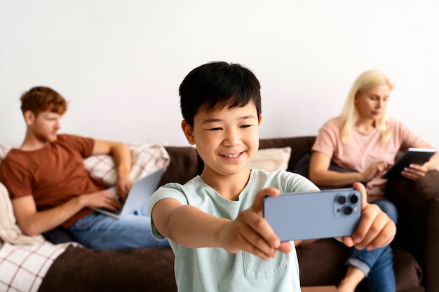 Niño sonriente de tiro medio tomando selfie