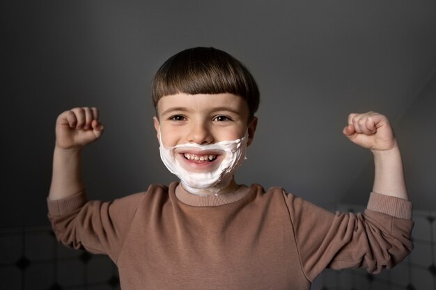 Niño sonriente de vista frontal con crema de afeitar