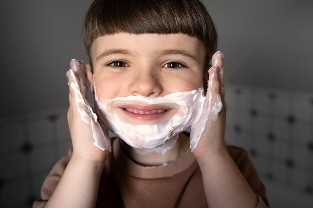 Niño sonriente de vista frontal usando crema de afeitar