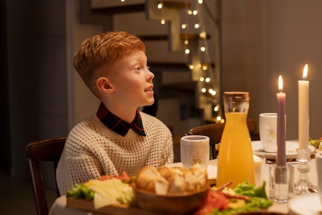 Foto gratuita niño sonriente de vista lateral sentado en la mesa