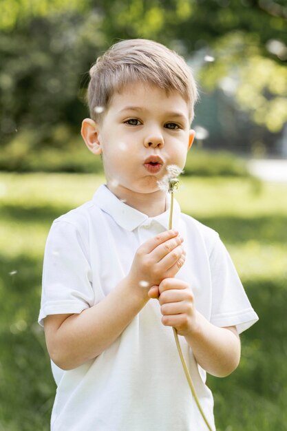 Niño soplando una flor en el viento