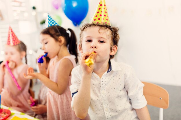 Niño soplando juguete de fiesta