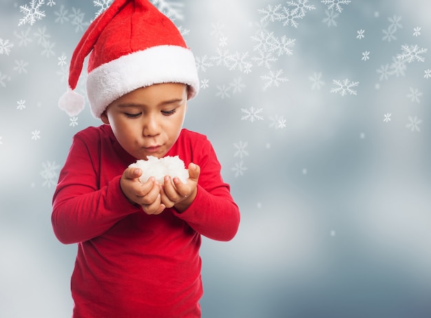 Foto gratuita niño soplando a la nieve en un fondo de copos de nieve