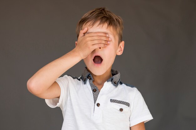 Niño sorprendido cubriendo sus ojos