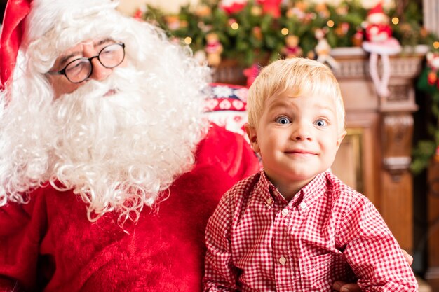 Niño sorprendido sentado en las piernas de papá noel