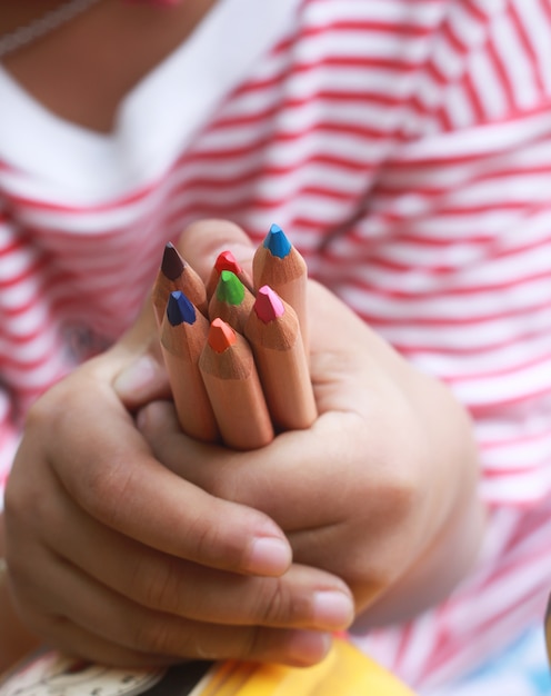 Niño sostenga lápices de color en la mano poco