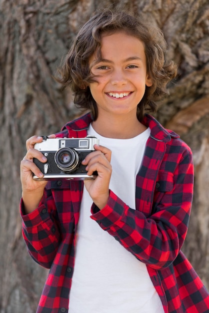 Niño sosteniendo la cámara mientras está al aire libre con los padres