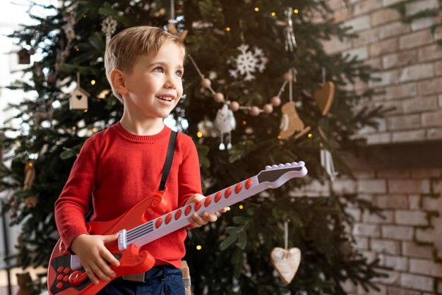 Niño sosteniendo una guitarra con espacio de copia