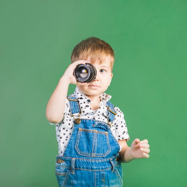 Niño sosteniendo la lente de la cámara en el ojo