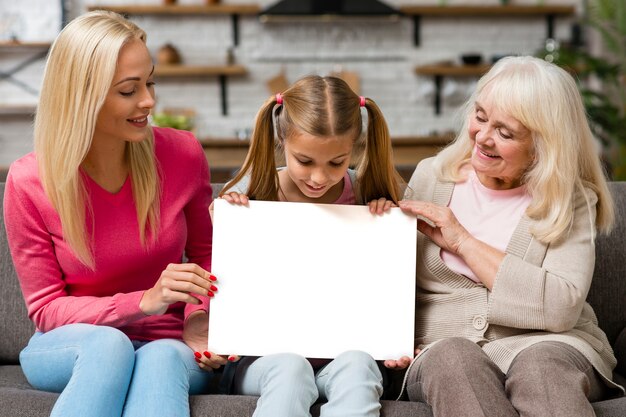 Niño sosteniendo una pancarta vacía junto a la madre y la abuela