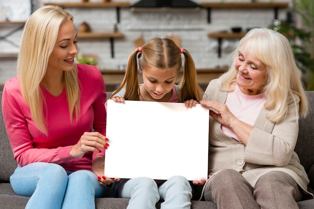 Niño sosteniendo una pancarta vacía junto a la madre y la abuela