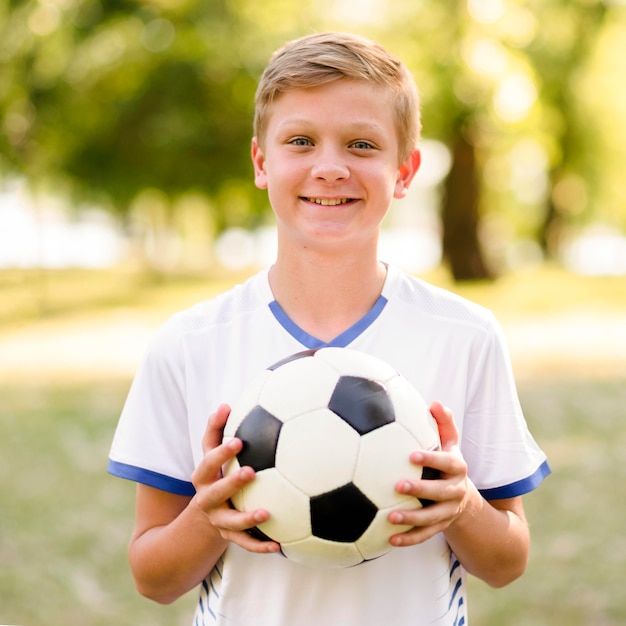 Niño sosteniendo una pelota de fútbol al aire libre