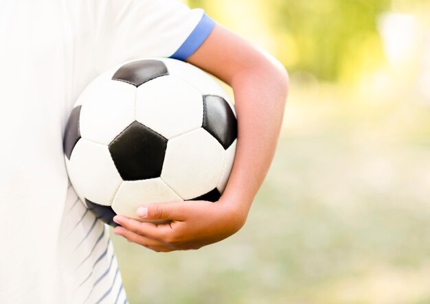 Niño sosteniendo una pelota de fútbol con primer plano de espacio de copia