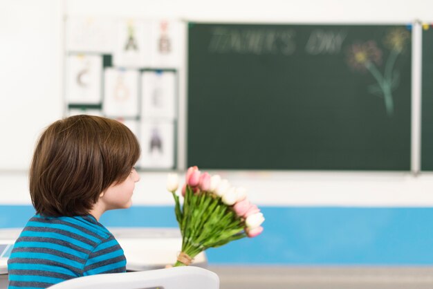 Niño sosteniendo un ramo de flores para su maestra