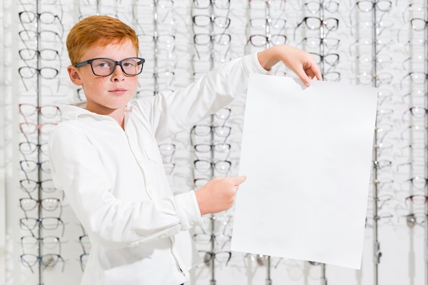 Niño sosteniendo y señalando papel blanco negro en tienda de óptica
