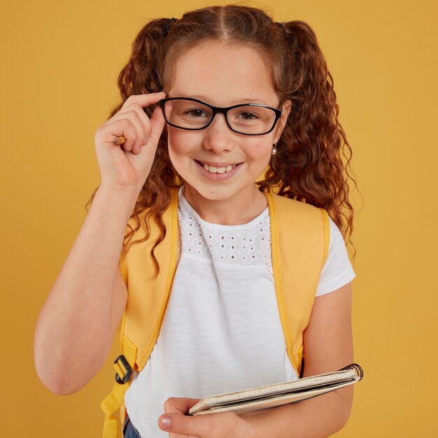 Niño sosteniendo sus gafas y un cuaderno