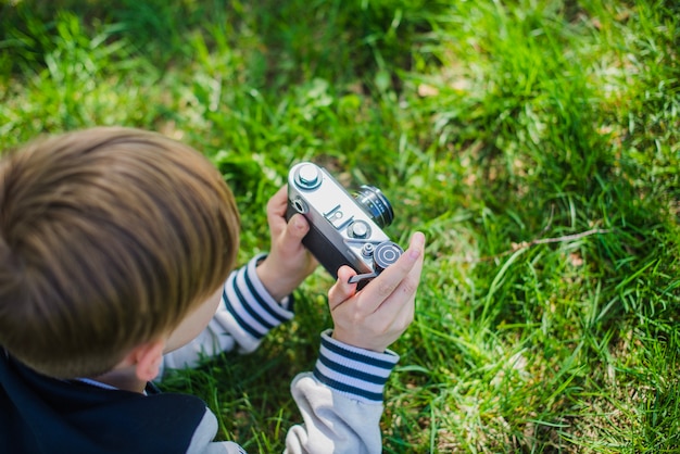 Foto gratuita niño con su cámara tumbado en el césped