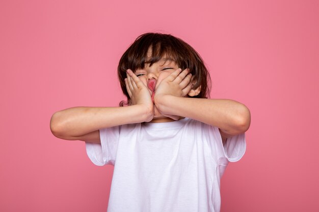 Niño con su mano saround su cara linda adorable en pared rosa