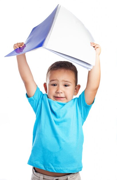 Niño sujetando una libreta en alto