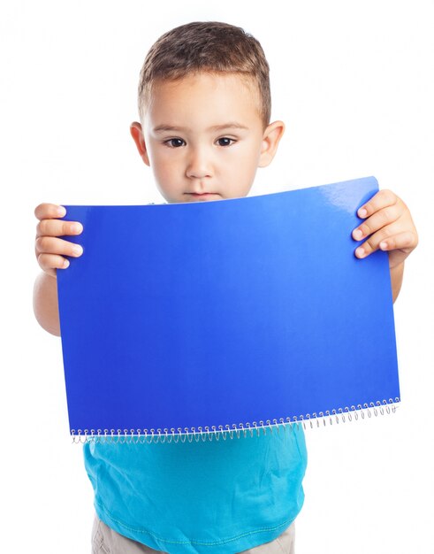 Niño sujetando una libreta delante suya