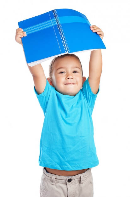 Niño sujetando una libreta por encima de su cabeza