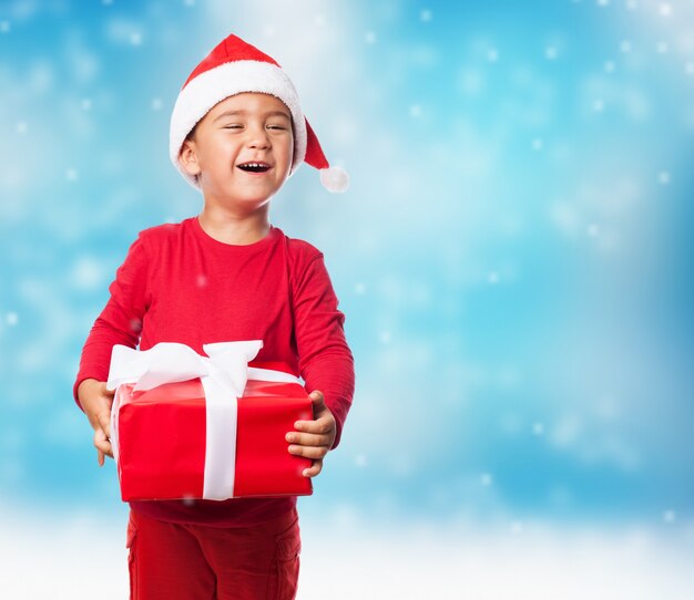 Niño sujetando un regalo en un fondo azul