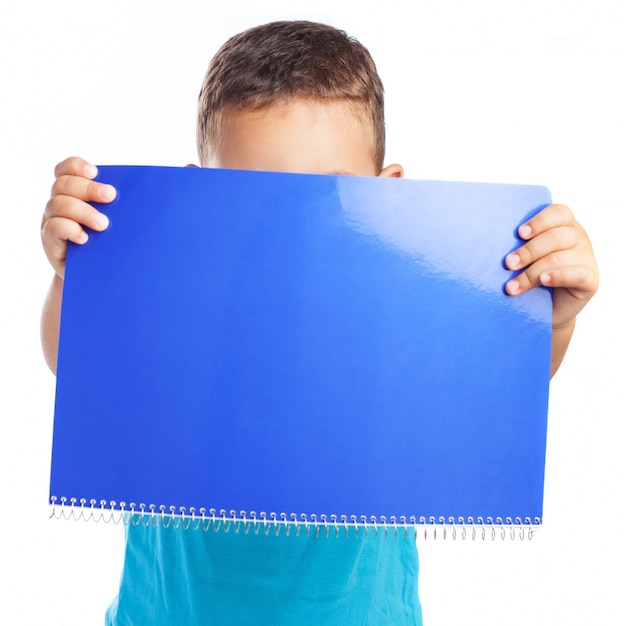 Foto gratuita niño tapando su cara con una libreta