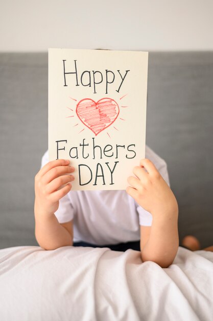 Foto gratuita niño con tarjeta de felicitación del día del padre