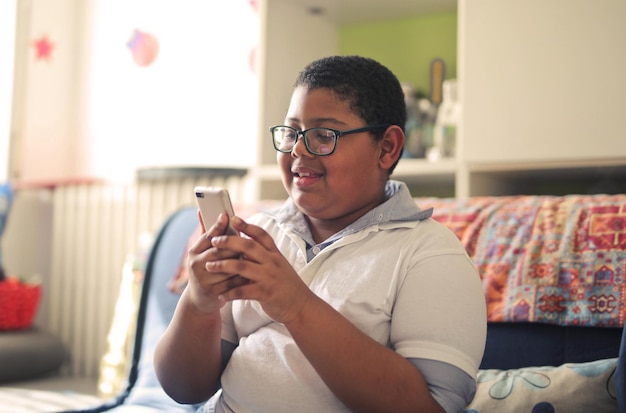 Foto gratuita un niño con teléfono inteligente en casa