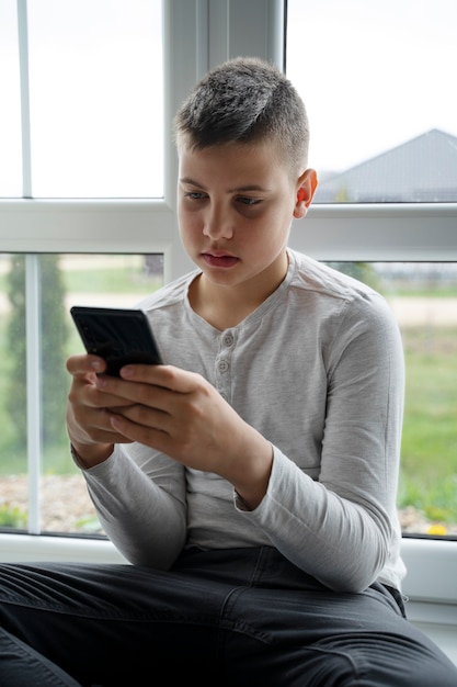 Foto gratuita niño con teléfono inteligente de tiro medio