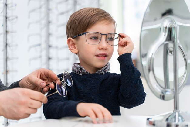 Niño en la tienda probándose gafas