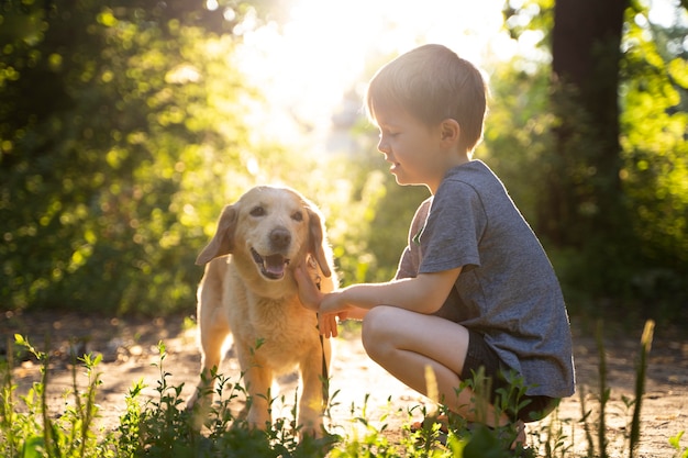 Niño de tiro completo acariciar a un perro al aire libre